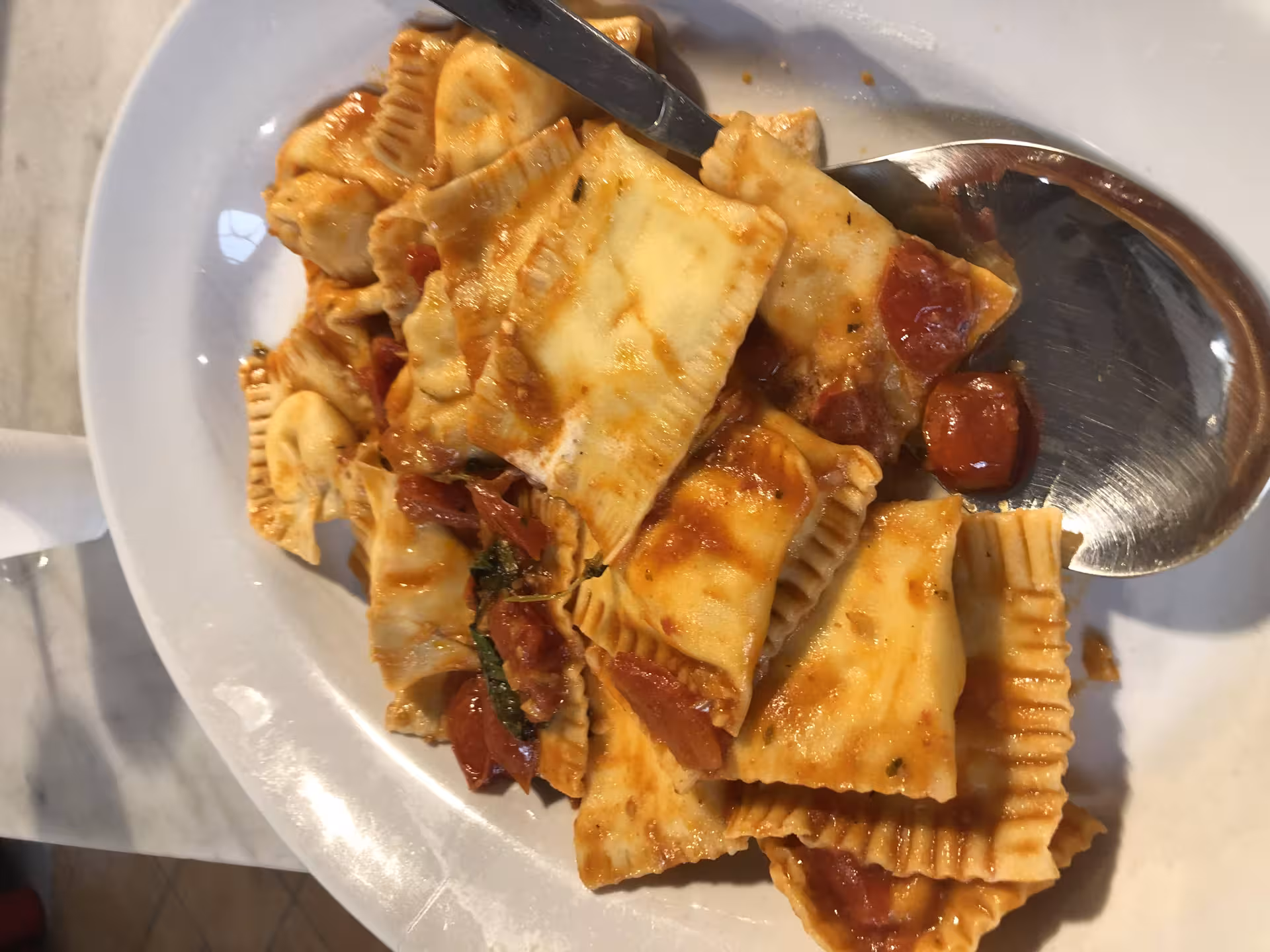 Delicious homemade ravioli in tomato sauce served on a white plate at a Tuscan cooking class in Florence.