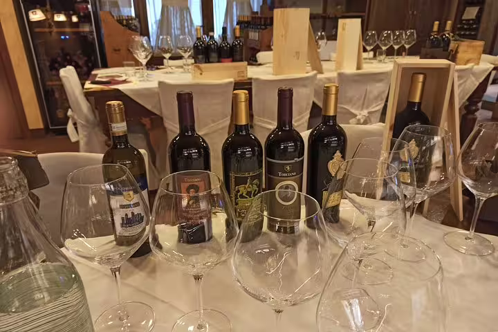 Selection of Tuscan red wines and empty glasses prepared for an intimate San Gimignano wine tasting on a private Livorno tour