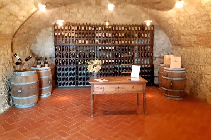 Rustic Tuscan wine cellar with barrels and bottle-lined walls, intimate setting for farm-to-table tasting on Pisa and Lucca tour