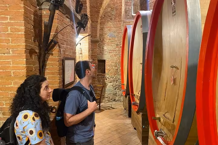 Visitors admiring large barrels in a rustic Tuscan winery on a Chianti wine tour.