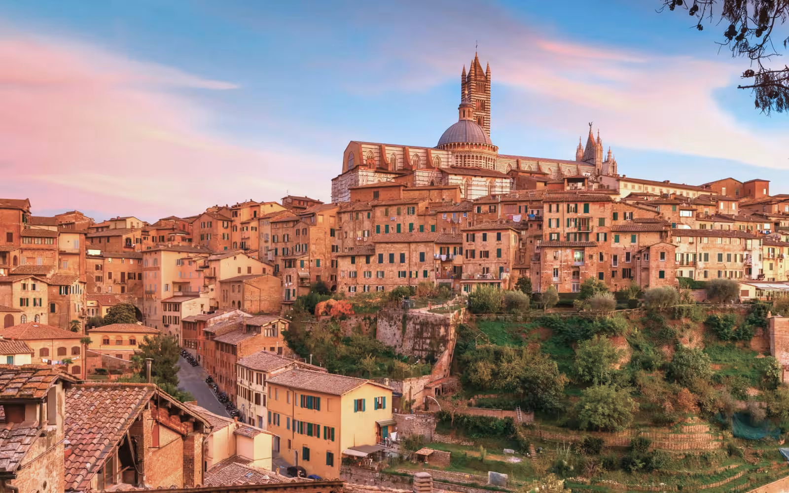 Scenic view of Tuscany's Siena at sunset, highlighting historic architecture on a supercar tour route.