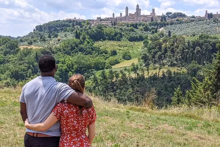 Couple embraces while enjoying panoramic view of San Gimignano's iconic skyline on Tuscany Tuk Tuk tour.