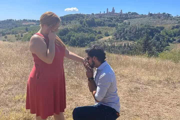 Romantic proposal with San Gimignano's towers in the background during a Tuscany Tuk Tuk tour experience.