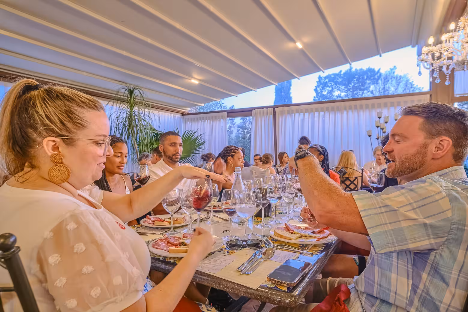 Group enjoying a lively dinner with wine and Italian cuisine on a Tuscany by Vespa tour from Florence.