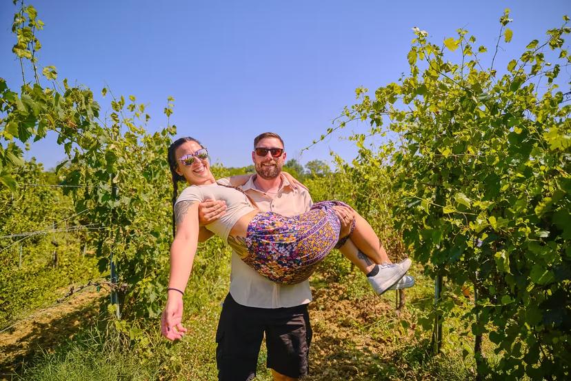 A couple enjoys a sunny day in a lush vineyard in Tuscany, highlighting wine tour experiences on the trip.