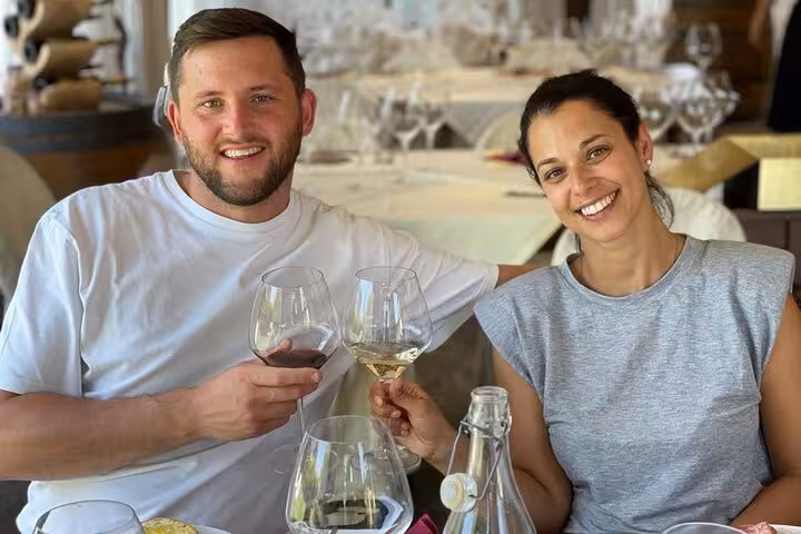 A couple toasting with glasses of wine during a relaxing meal on a Tuscany wine tour by Tuk Tuk.