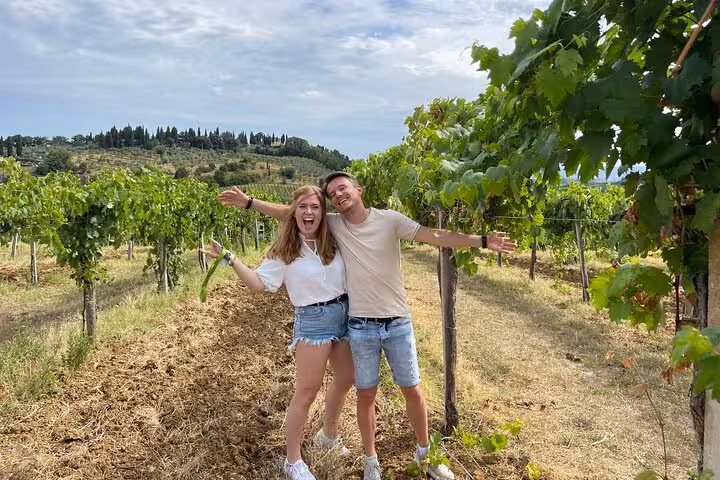 Happy couple posing in a lush Tuscany vineyard, celebrating their wine tour experience.