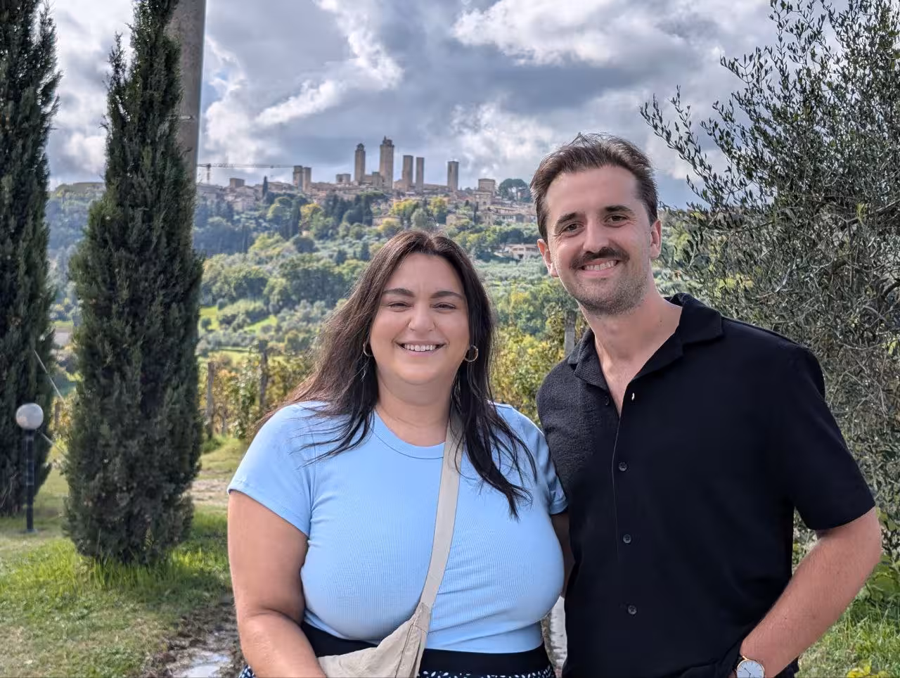 Smiling tourists with San Gimignano towers in the background on a Tuscany winery tour from Florence.