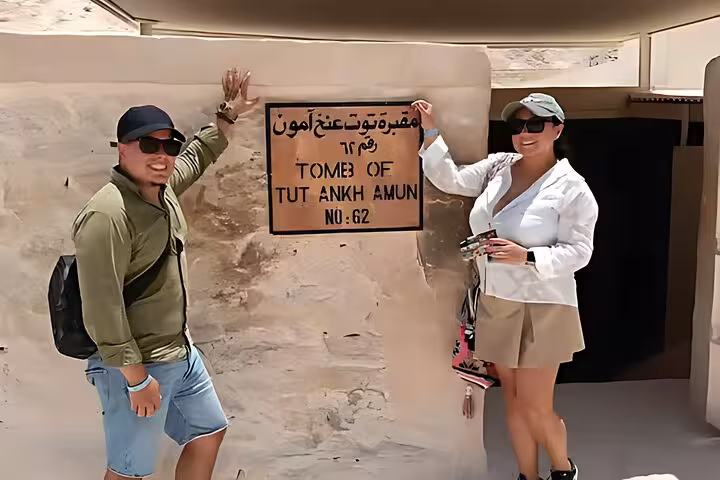 Travelers at Tutankhamun tomb entrance sign, Valley of the Kings, Luxor day tour from Cairo by plane