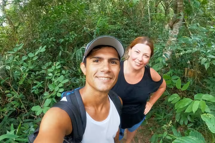 Two hikers smiling amidst lush greenery on the scenic trail of Two Brothers hike in Rio de Janeiro.