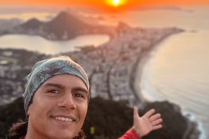 Hiker enjoying a stunning sunset view over Rio de Janeiro from the summit of Two Brothers mountain.