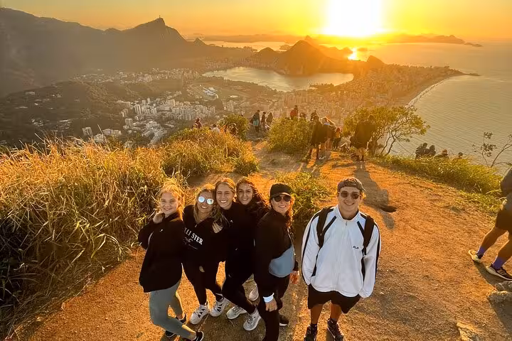 Group enjoying sunset with panoramic view of Rio from Two Brothers hike in Vidigal, highlighting the breathtaking scenery.