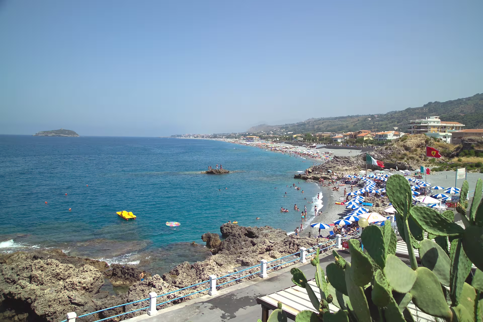 Panoramic view of the Tyrrhenian coast in Cosenza with rocky shore, umbrellas, clear sea and lively summer beach clubs