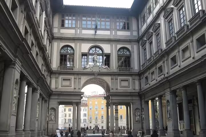 Guided tour group walking through the grand courtyard of the Uffizi Gallery in Florence on a skip-the-line combo visit