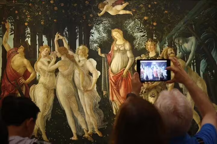 Tourists admire and photograph Botticelli’s Primavera during a guided skip-the-line tour of the Uffizi Gallery in Florence