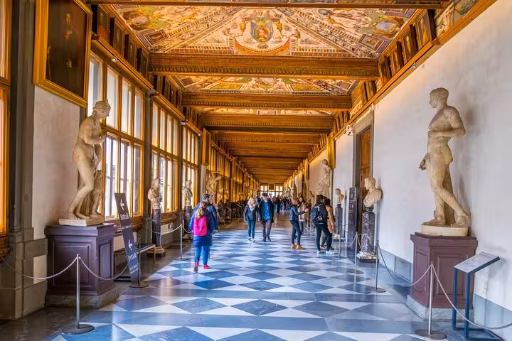 Discover the Uffizi Gallery's ornate corridor adorned with classical statues and intricate ceiling art in Florence's iconic museum.
