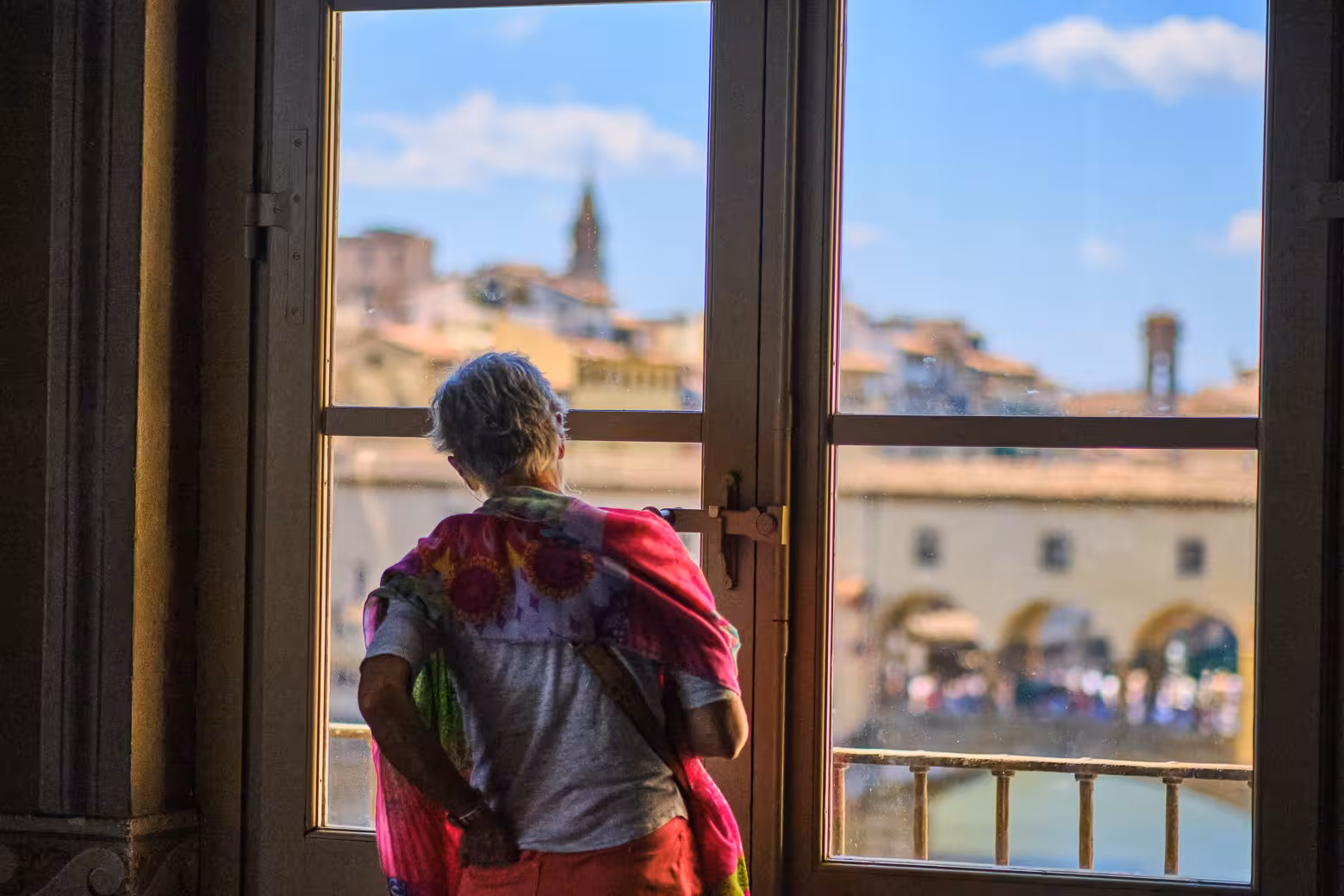 Tourist admires scenic views of Florence from a window during the Uffizi Gallery guided experience.