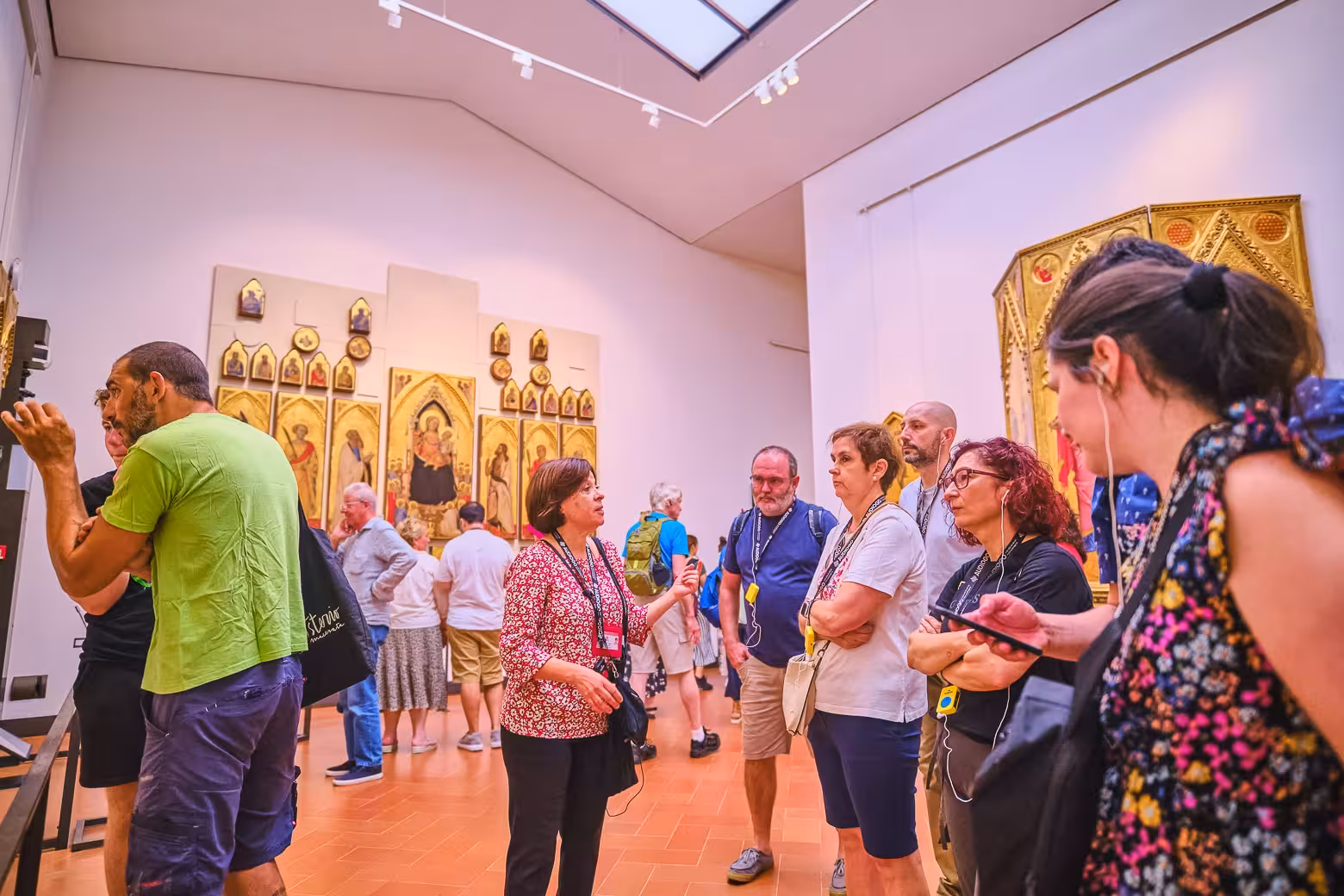 Group listens attentively to a guide in a room filled with iconic artwork during the Uffizi Gallery tour in Florence.