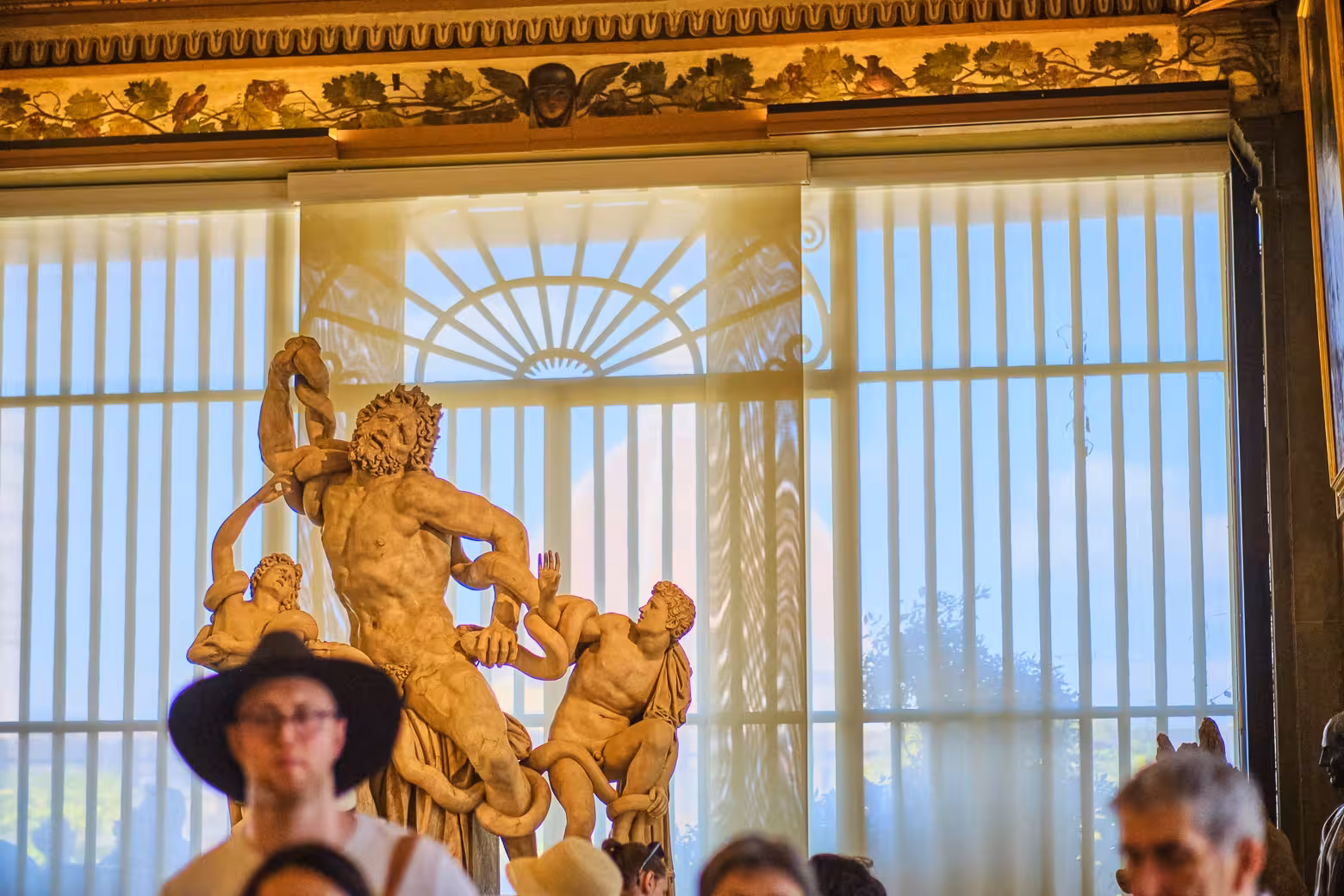 Tourists view the Laocoön sculpture in Uffizi Gallery's grand room, enjoying skip-the-line access on private tour.