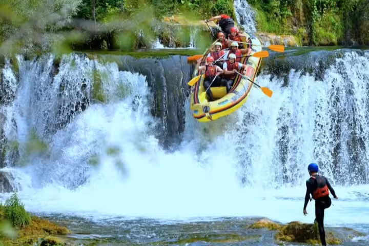 Raft plunging over Una River waterfall at Štrbački Buk on the rafting tour from Plitvice Lakes National Park