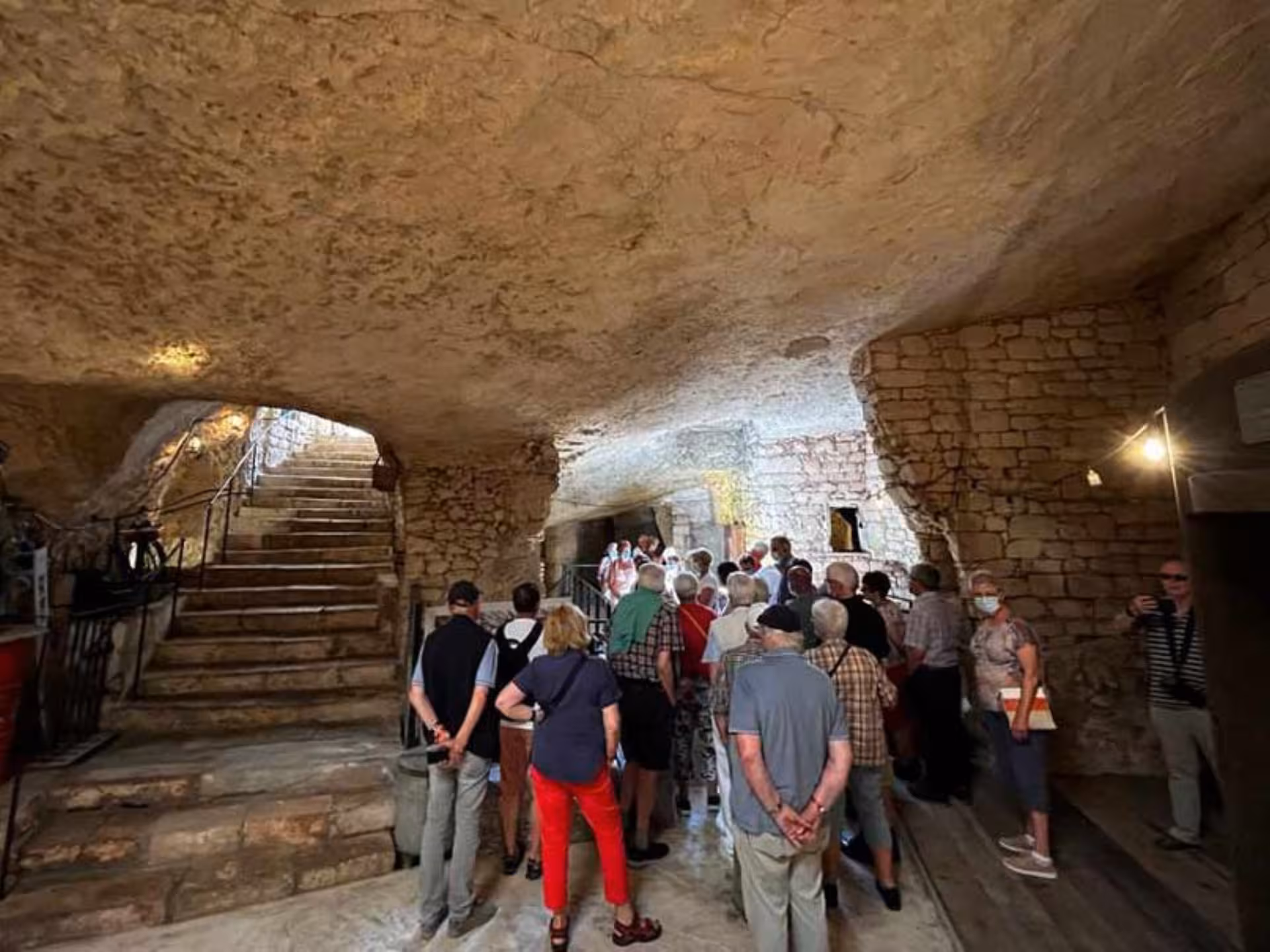 A group of tourists explores an ancient underground mill with stone walls and staircases near Alberobello and Ostuni.