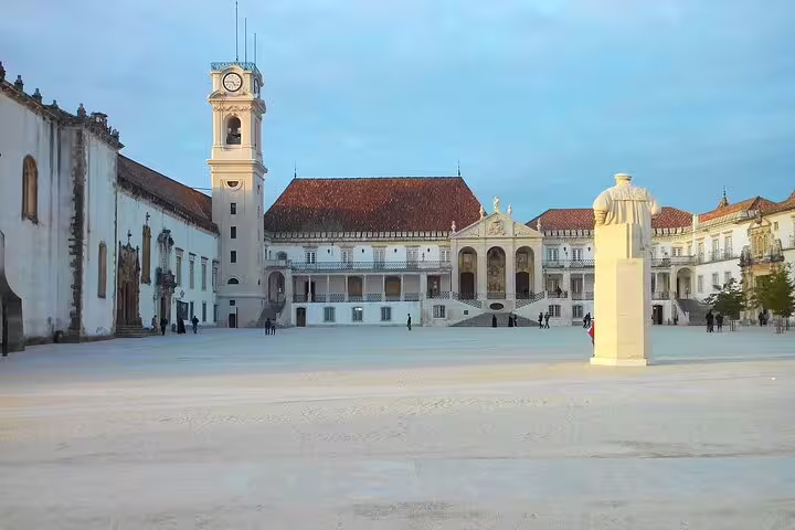University of Coimbra courtyard with clock tower under a blue sky, ideal stop on a Lisbon to Coimbra private journey.