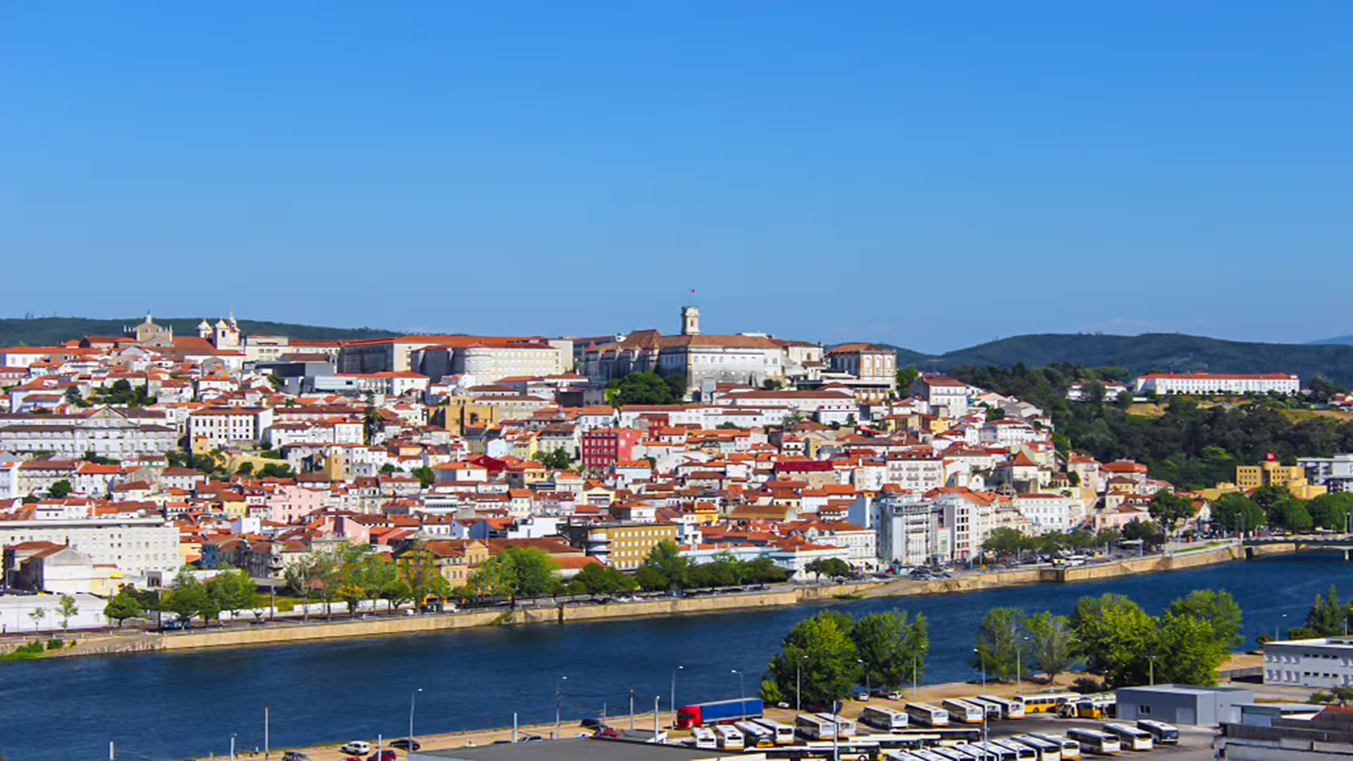 Panoramic view of the historic University of Coimbra and surrounding cityscape, highlighting the scenic riverfront in Portugal.