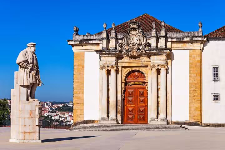 Statue and grand entrance of the University of Coimbra, showcasing historical landmarks on a guided city walk.