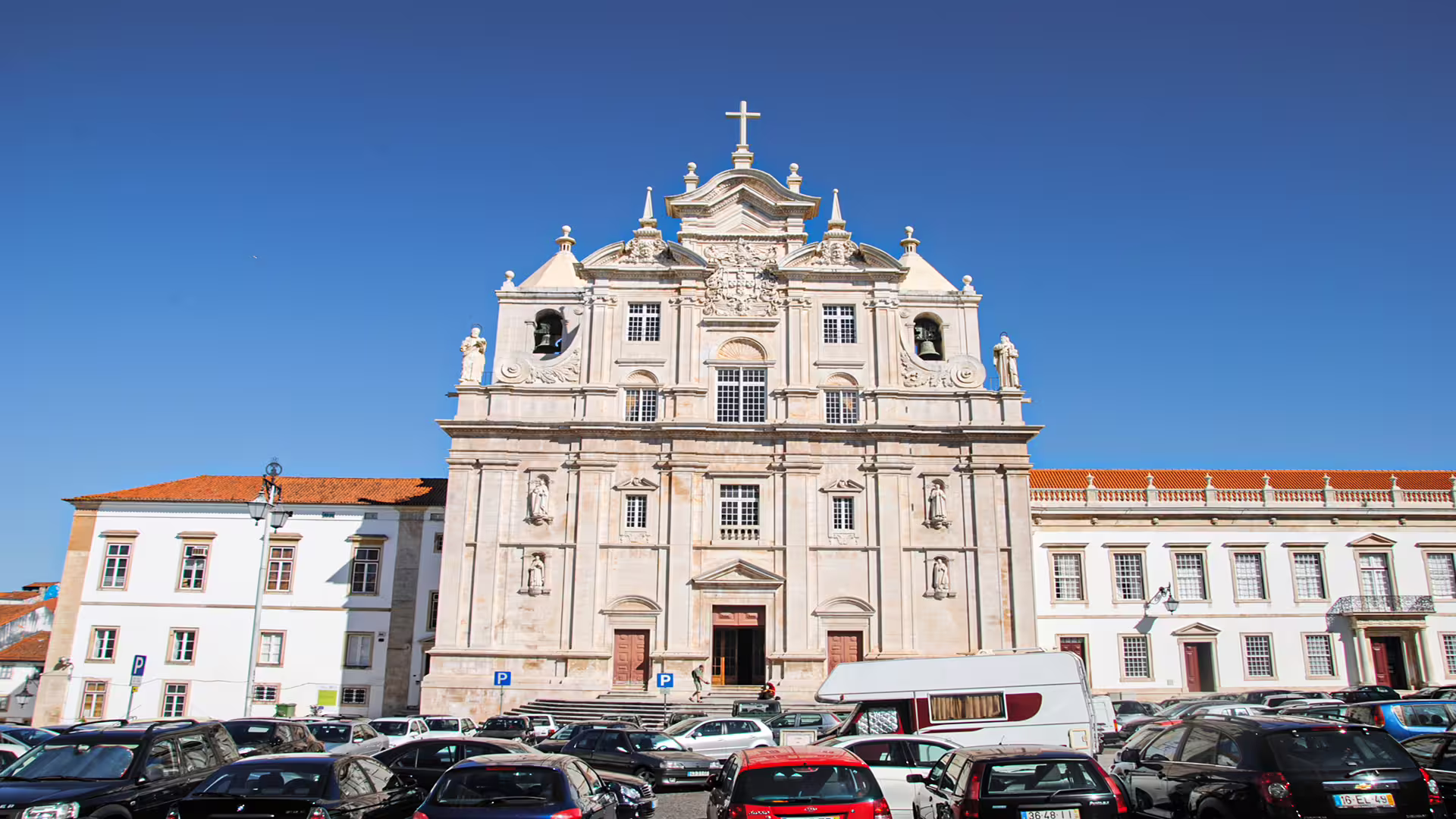 Facade of the historic University of Coimbra building under a clear blue sky, showcasing stunning architecture on a private tour.