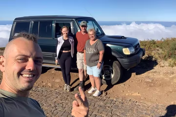 Group enjoying scenic mountain view with off-road vehicle on The Untraveled West Tour adventure.