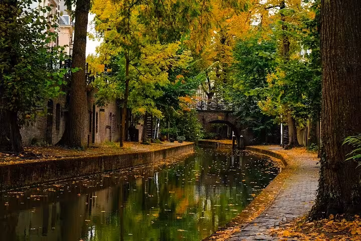 Autumn canal path in Utrecht with trees and historic bridge, scenic stop on small-group guided tour