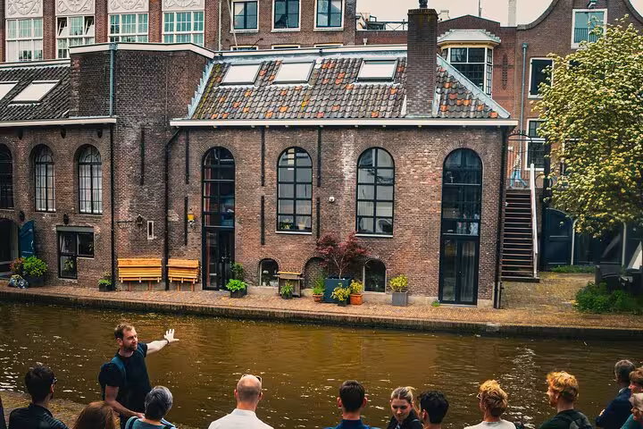 Guide presenting Utrecht canal-side architecture to a limited-size group on a city walking tour with extras