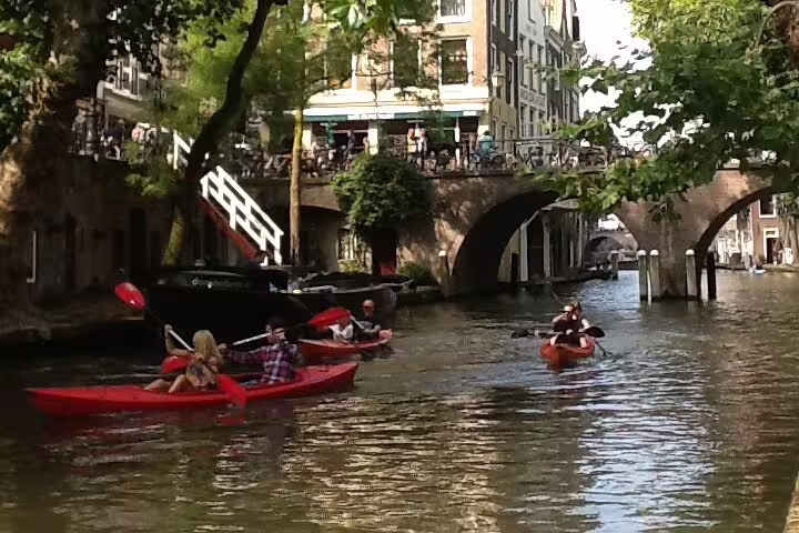 Kayakers on Utrecht canal under old stone bridge, highlight of “Your Own Utrecht” private tour