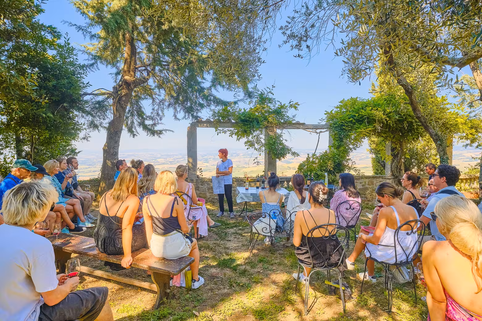 Group enjoying a wine tasting session under the shade in Val D'Orcia's scenic countryside.