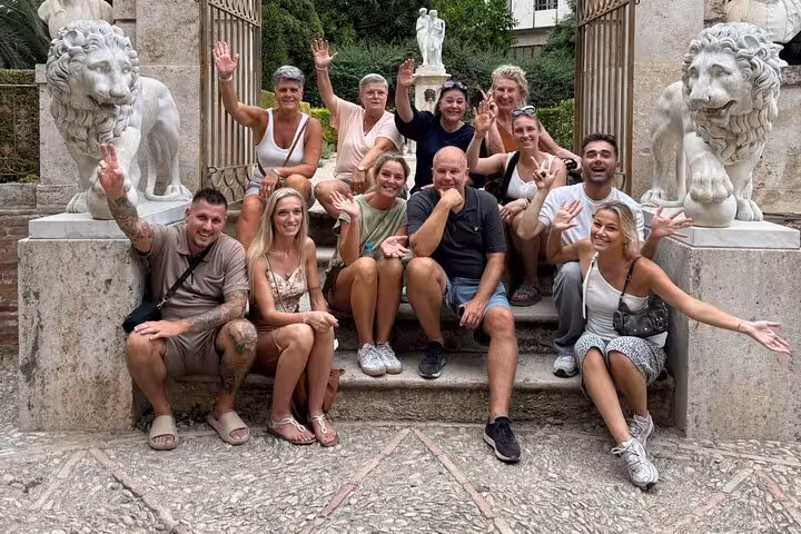 Happy group on Dutch Valencia bike tour posing by stone lion statues in a historic garden entrance