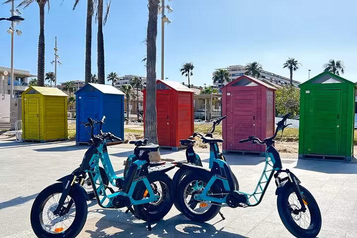Valencia e-bike tour bikes parked by colorful beach huts near the seafront on route to City of Arts and Sciences