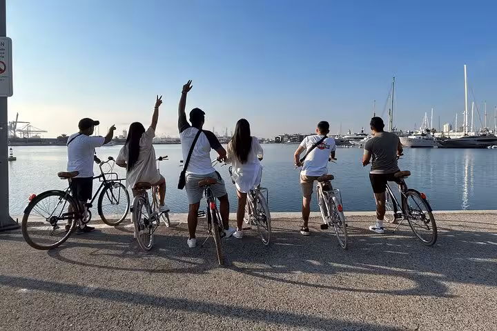 Group on bikes at Valencia Marina watching yachts, Valencia by land and sea e-bike tour plus catamaran cruise