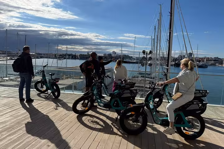 Group on Valencia e-bike tour at the marina, overlooking sailboats before catamaran cruise adventure