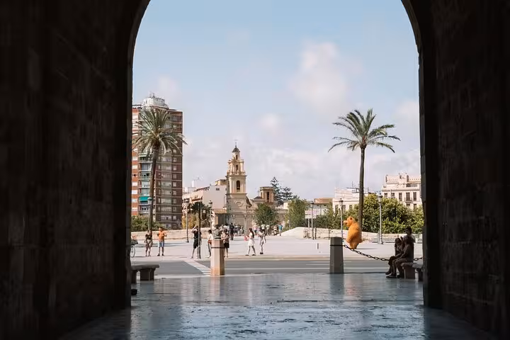 View through a historic Valencia archway toward palm-lined plaza, a scenic stop on the e-bike tour