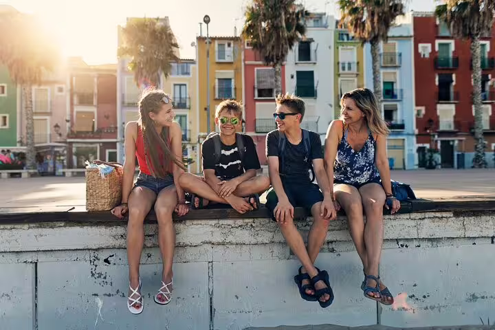 Family enjoying a sunny day on a Valencia private tour, with colorful buildings and palm trees in the background.