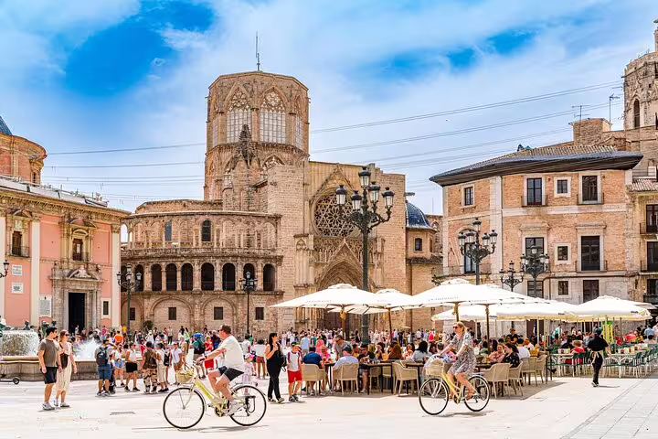 Cyclists enjoy a sunny day in Valencia's historic square during a private bike and e-bike tour with drinks included.