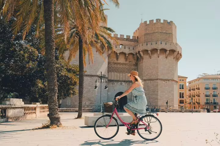 Woman enjoying a Valencia private bike tour near historic Torres de Serranos, highlighting the charm of the city's landmarks.