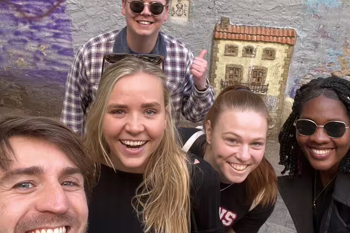 Friends smiling on Valencia Iconic Sights scavenger hunt, posing by street art in the old town
