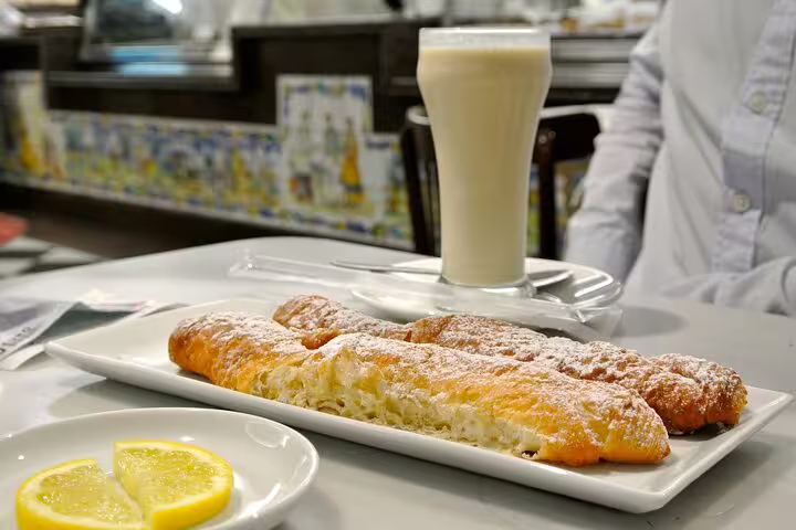 Traditional Valencian pastries and a refreshing glass of horchata on a table, perfect for a local tasting experience on a Valencia tour.