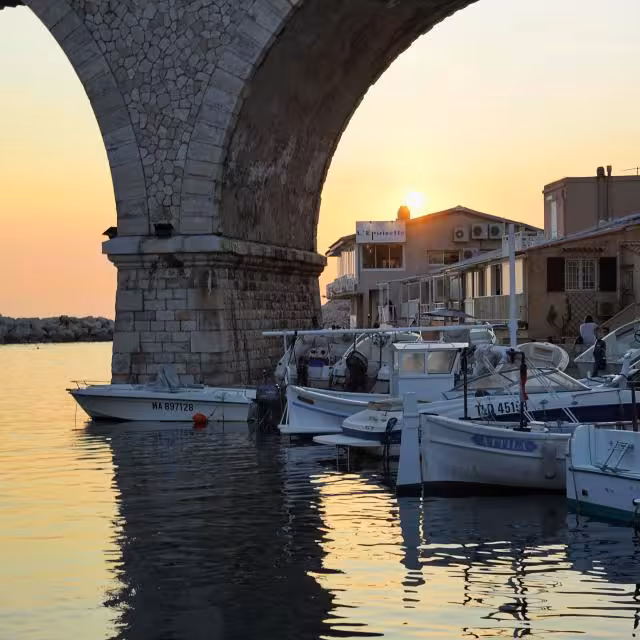 Sunset at Vallon des Auffes harbor under stone arch, Marseille sea walk on urban hiking tour route