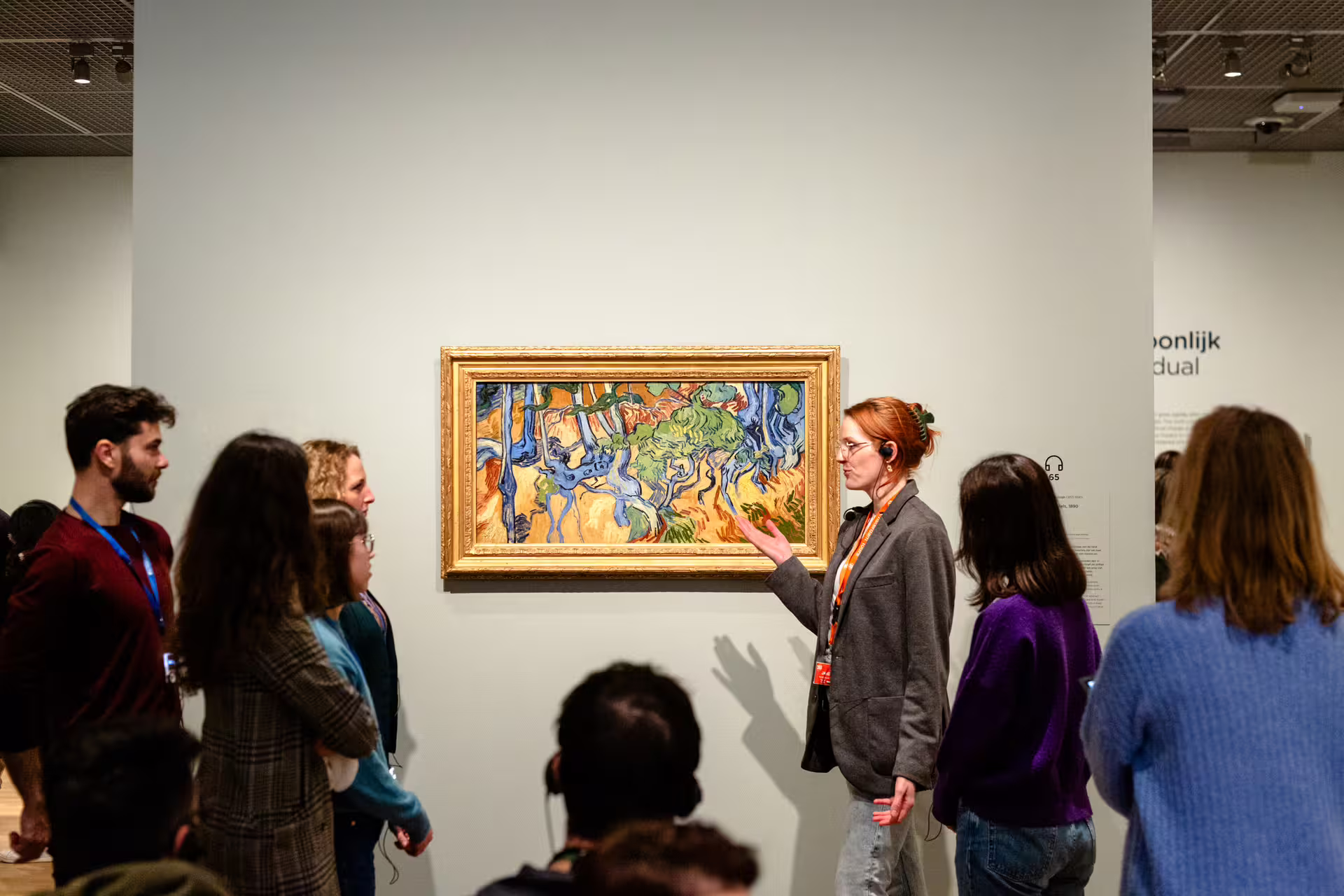 Visitors engage with a guide during a Van Gogh painting tour, showcasing vibrant artwork in an immersive museum experience.