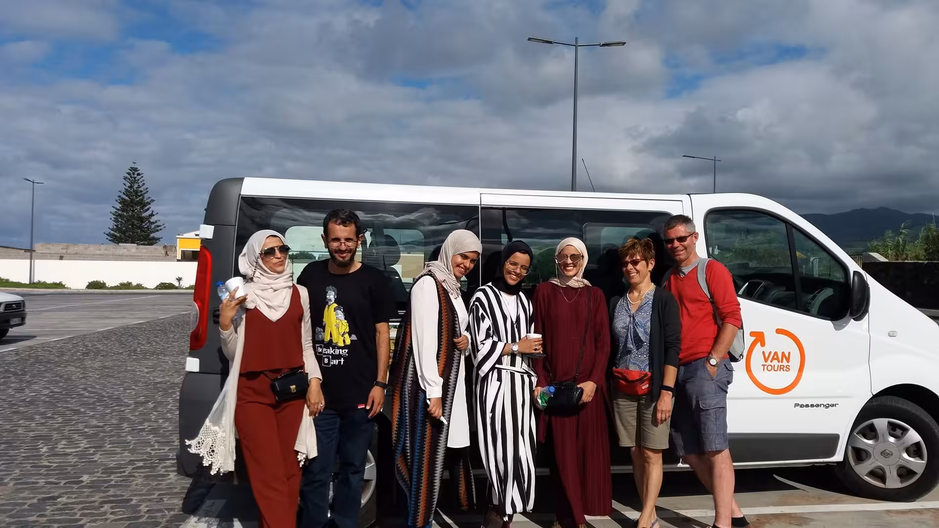 Happy group posing beside a Van Tours vehicle before exploring Sete Cidades and Lagoa do Fogo on a full-day Azores trip
