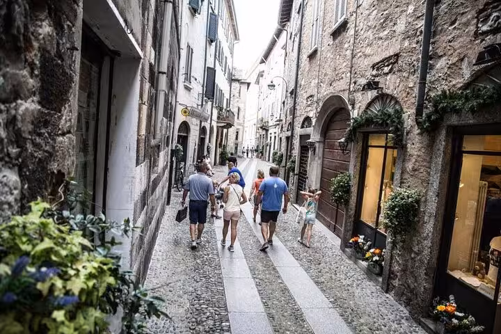 Visitors strolling a narrow cobbled street in Varenna, Lake Como cruise day trip from Milan itinerary