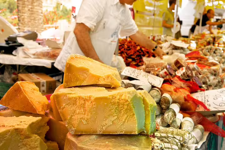 Close-up of Italian cheeses and cured meats at a vibrant Vatican market stall, highlighting authentic food tasting and cooking class experiences.