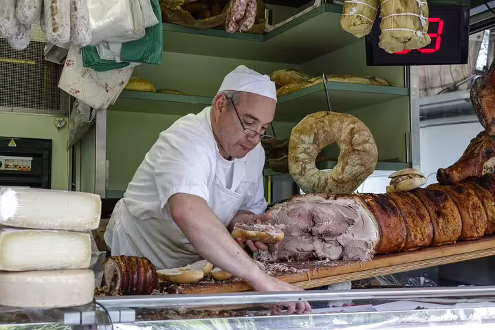 Artisan chef prepares traditional Italian porchetta at a bustling Vatican market stall, highlighting authentic culinary experiences.